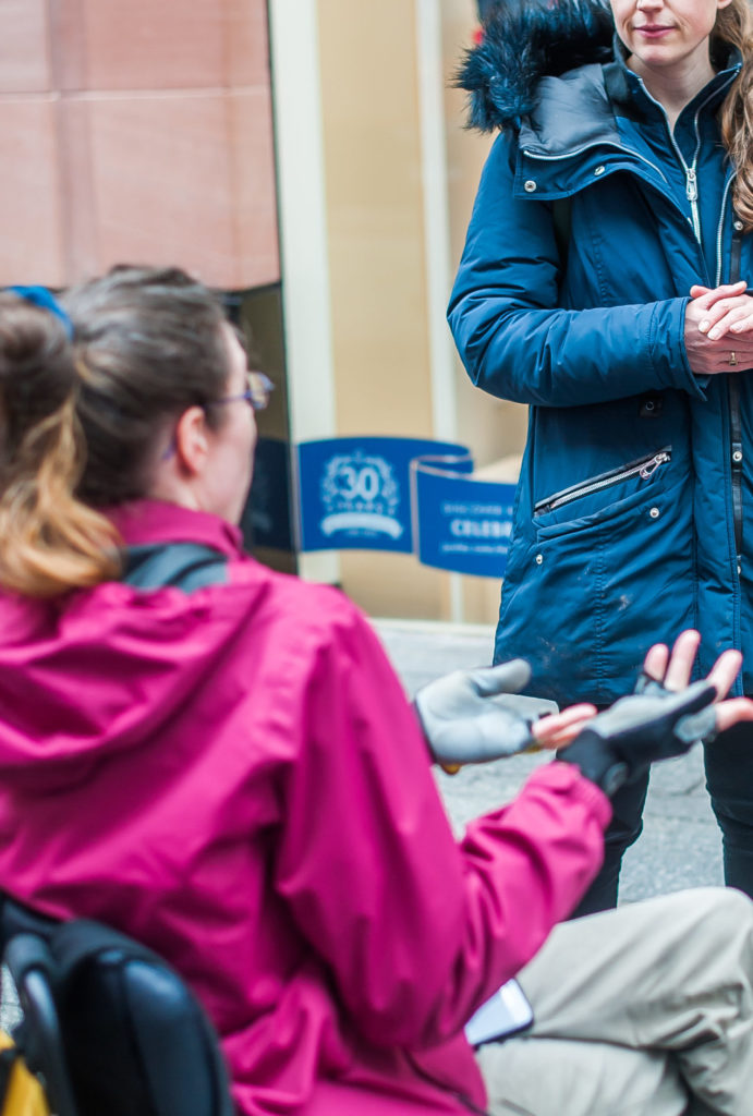 Woman in wheelchair talking to woman outside a building