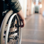 left hand image we see the side of a person in a wheelchair wheeling down a well lit corridor, looks like a health care establishment.