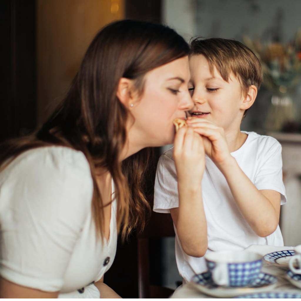 Woamn with little boy feeding her a biscuit