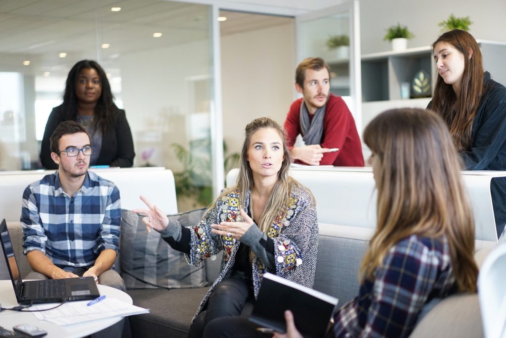 Group of people, girl in middle chatting to friend or work colleague