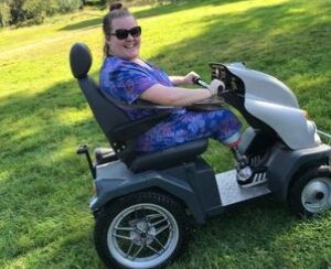 Jodie sits in a tramper surrounded by grass