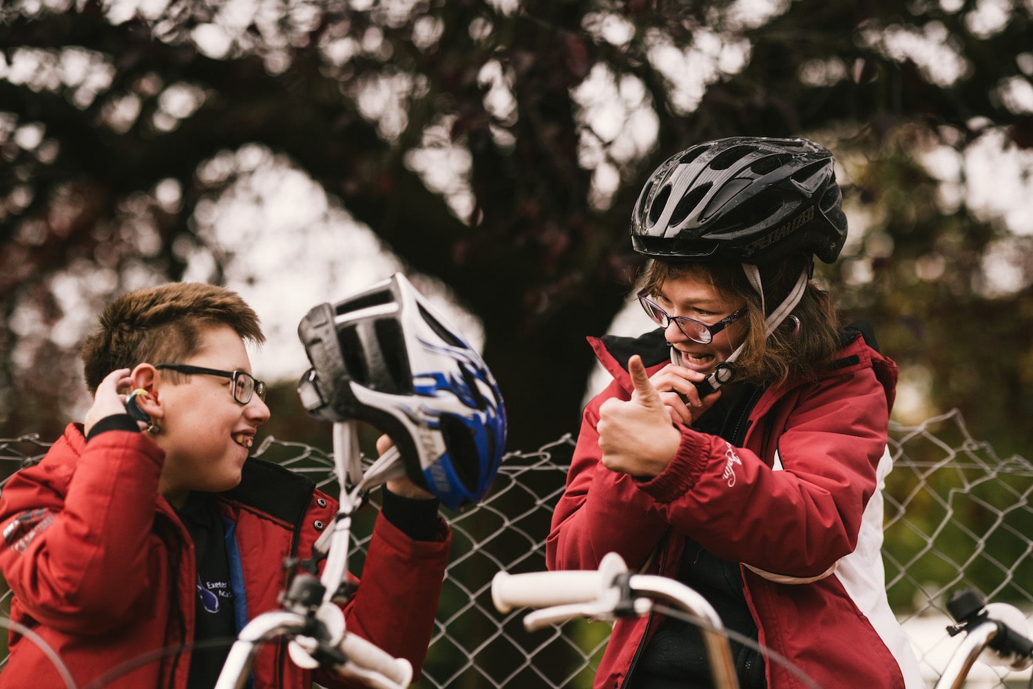 Two children on bikes signing to each other outside at the Deaf Academy