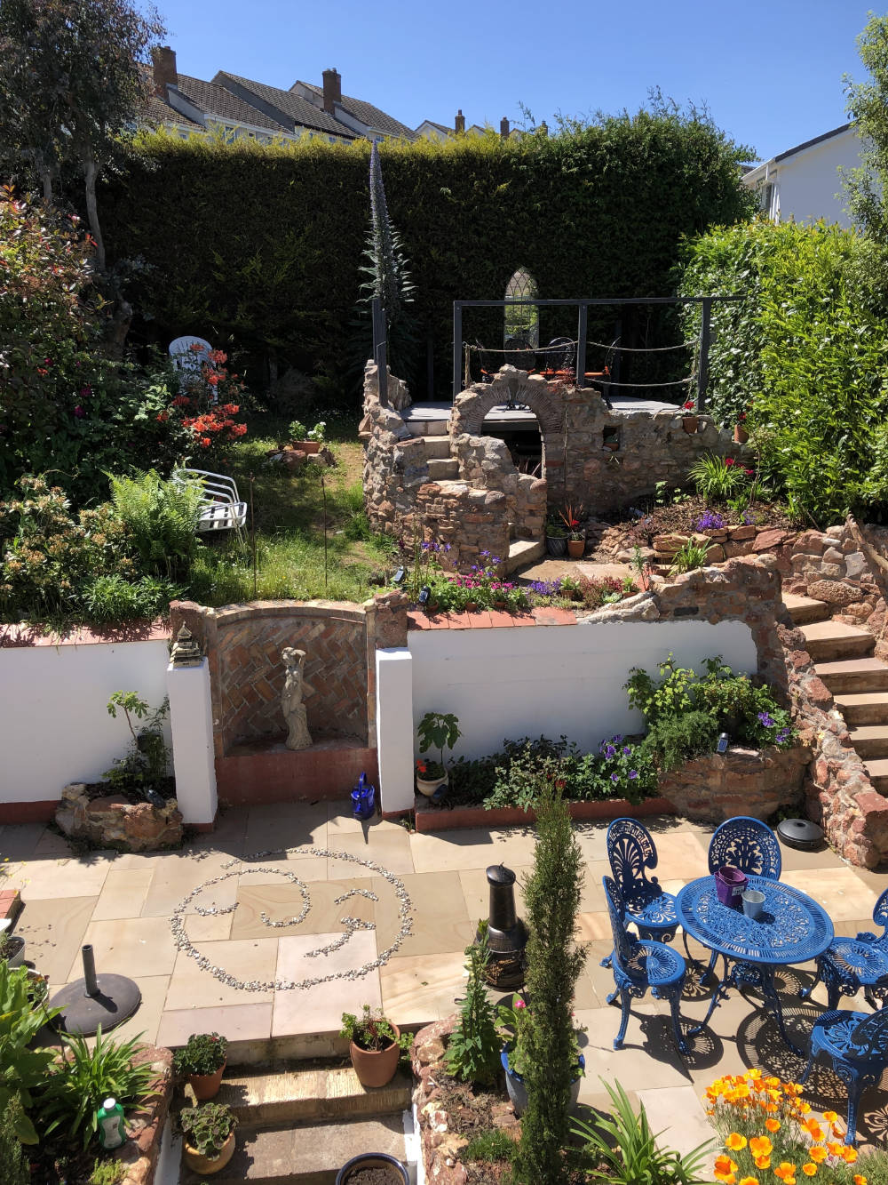 terraced garden with stone walls flowers and patio with George icon made of pebbles