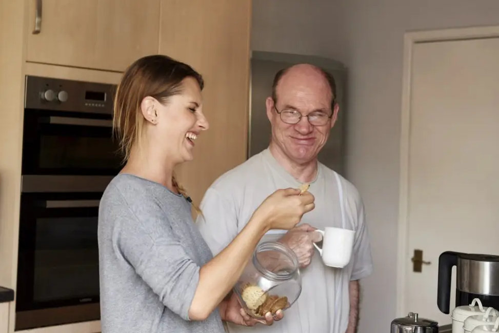 Apprentice carer supporting a man making tea