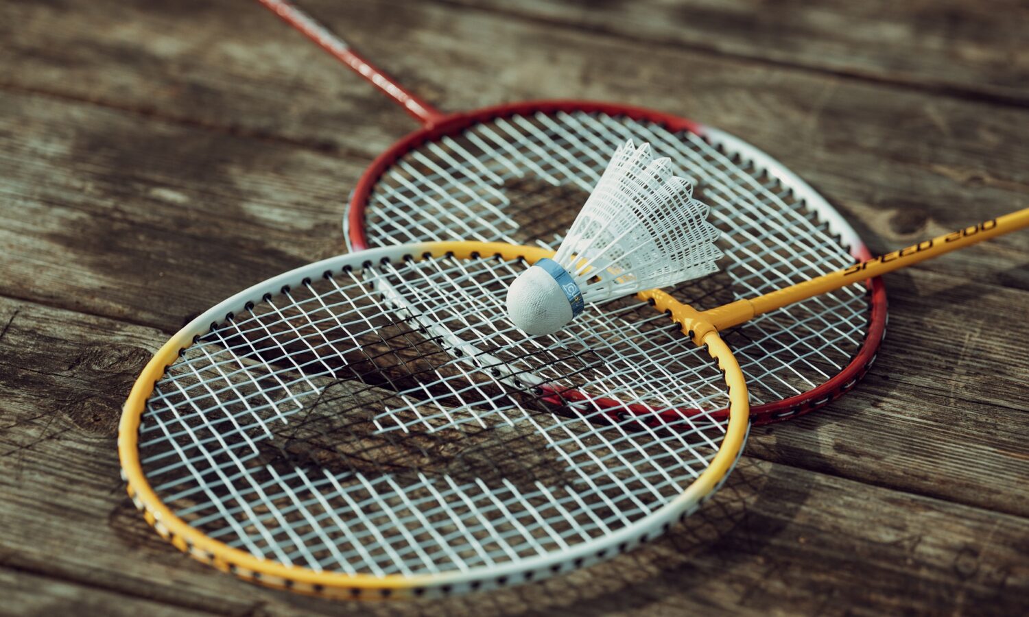 Two badminton racquets with a shuttlecock on the ground