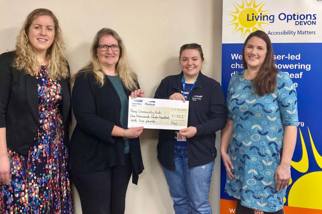 Members of staff standing in a line being presented a cheque