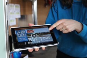A tablet held by a person is showing an audio tour ready to play