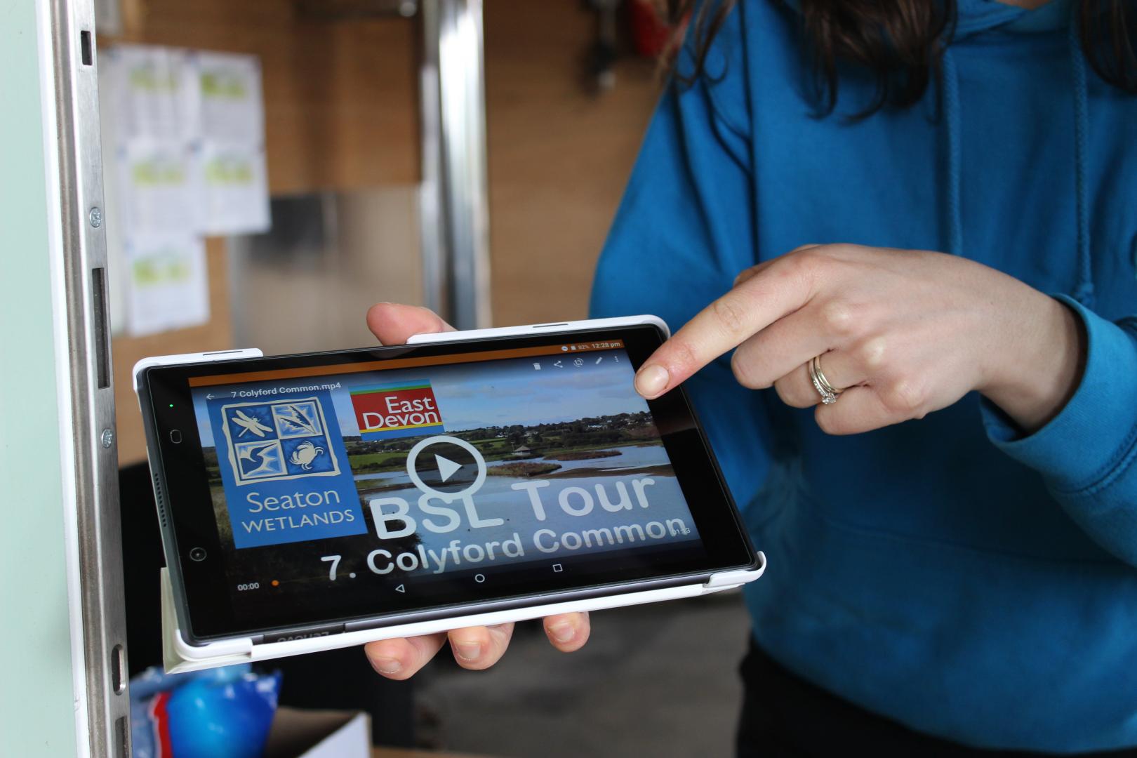 A tablet held by a person is showing an audio tour ready to play