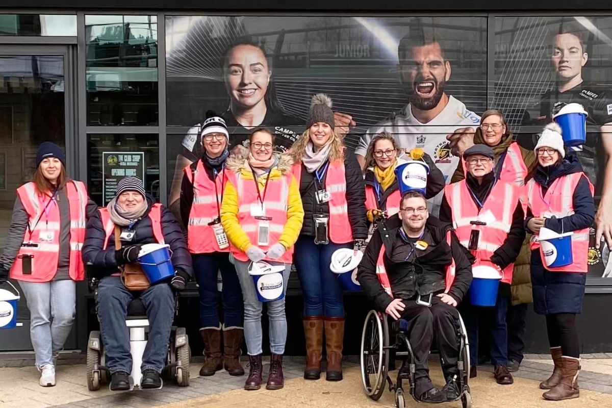 The LOD team stand outside the Exeter Chiefs stadium in tabards with fundraising buckets