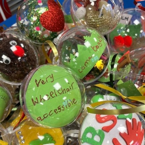 A selection of christmas baubles one says come together inside and another says very wheelchair accessible