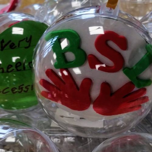 A bauble with a decoration inside with the letters BSL and two signing hands 