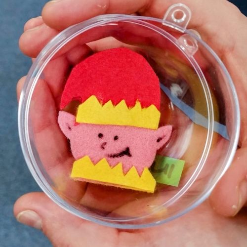 A handmade felt elf in a clear bauble