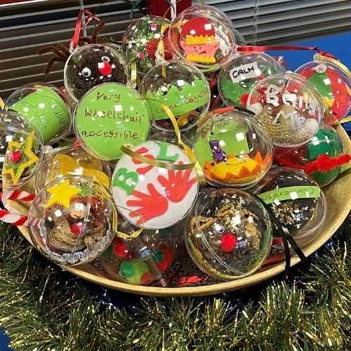 Colurful christmas tree baubles in a bowl surrounded by tinsel