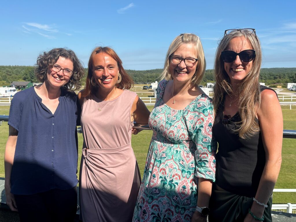 Our counselling team smiles posing for a picture in front of the racecourse.